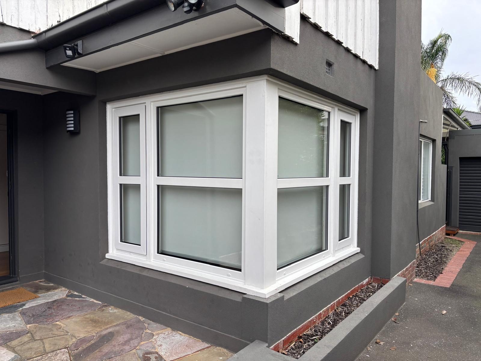 White bay window installed on a dark rendered façade